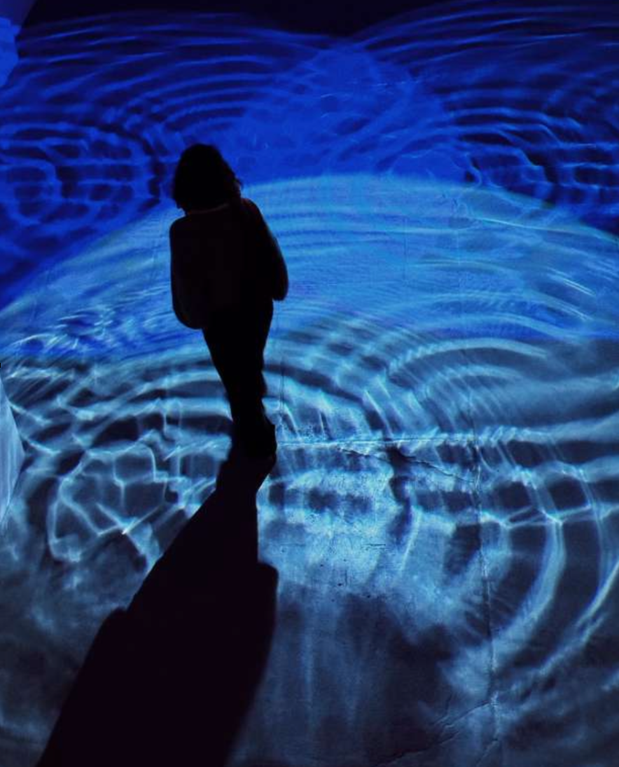 A person is walking through blue waves of light on the floor.